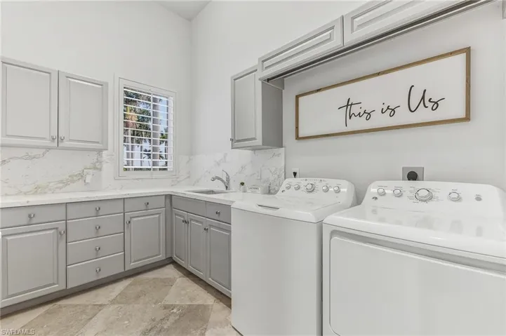 Laundry room with washing machine and clothes dryer, stone tile flooring, and cabinet space