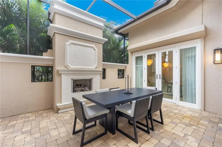 View of patio featuring an outdoor fireplace, outdoor dining space, a lanai, and french doors