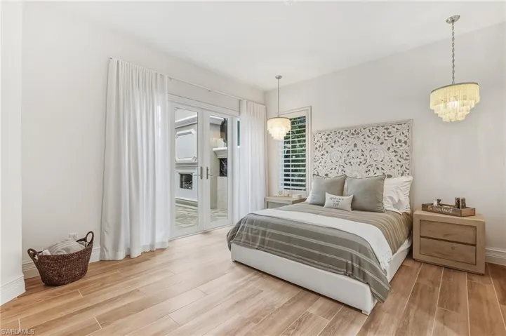Bedroom featuring wood finish floors, access to outside, and a chandelier