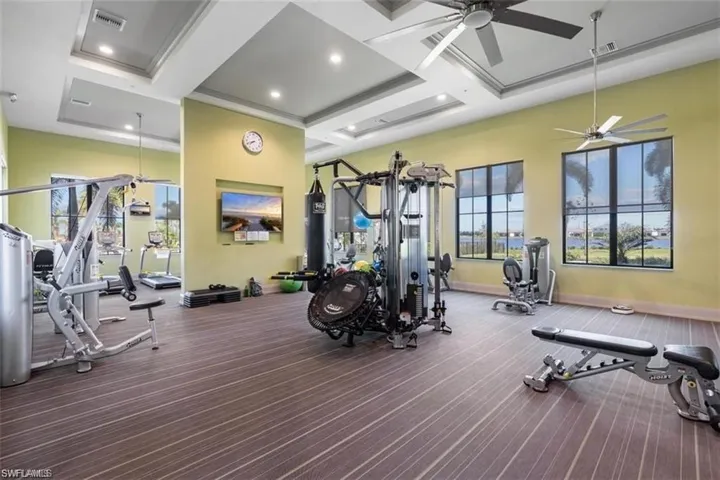 Workout area with a ceiling fan, coffered ceiling, baseboards, beam ceiling, and carpet floors
