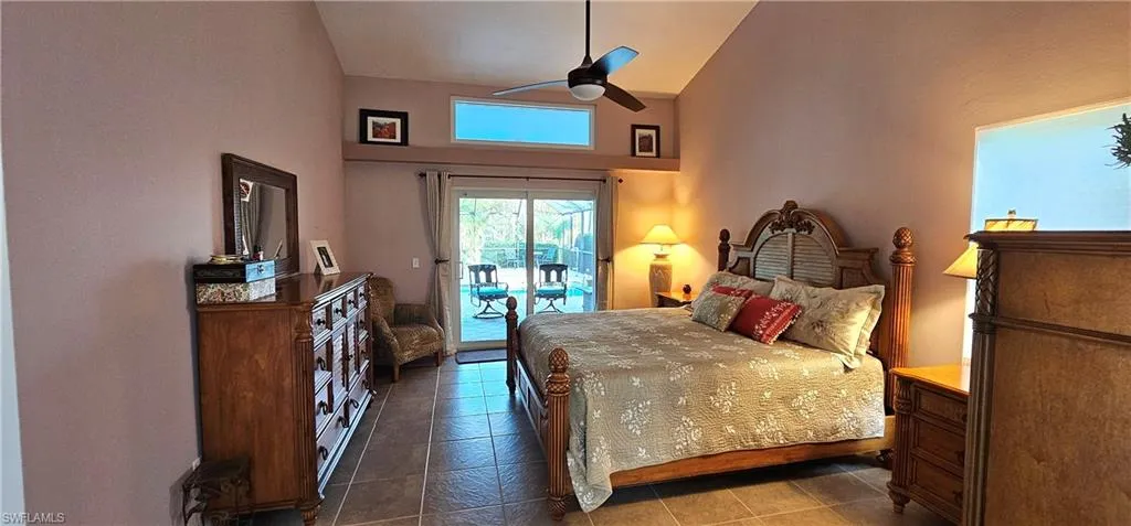 Bedroom featuring access to outside, dark tile patterned flooring, ceiling fan, and high vaulted ceiling