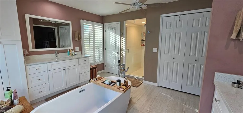 Bathroom with vanity, shower with separate bathtub, hardwood / wood-style floors, and ceiling fan