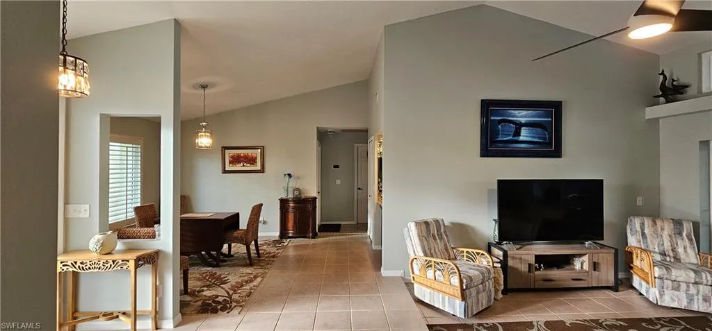 Living room with tile patterned flooring and vaulted ceiling