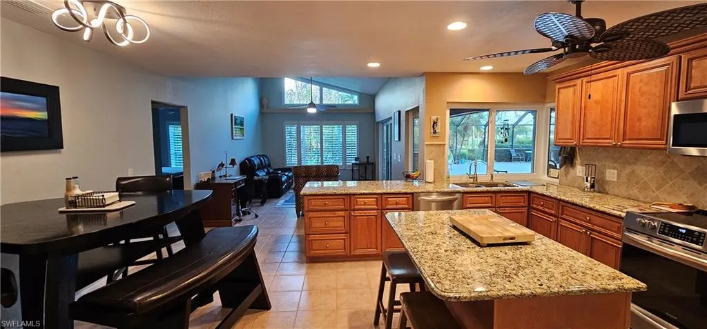 Kitchen with stainless steel appliances, light tile patterned flooring, a breakfast bar, tasteful backsplash, and a center island