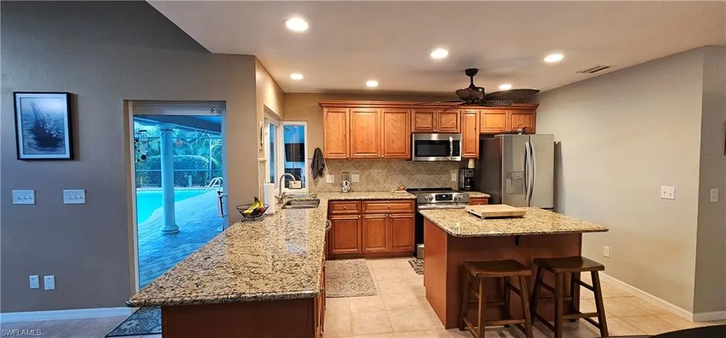 Kitchen with stainless steel appliances, kitchen peninsula, sink, tasteful backsplash, and ceiling fan