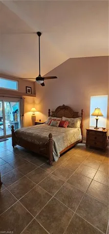 Bedroom featuring dark tile patterned floors, access to outside, vaulted ceiling, and ceiling fan