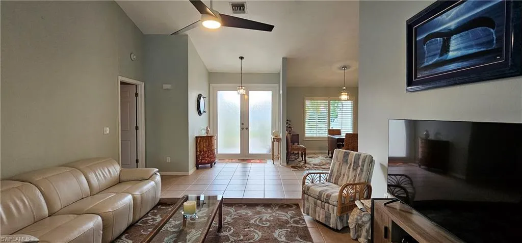 Living room featuring french doors, light tile patterned floors, and ceiling fan