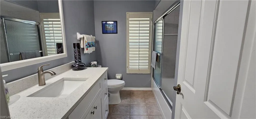 2nd Full bathroom with vanity, enclosed tub / shower combo, tile patterned floors, and toilet