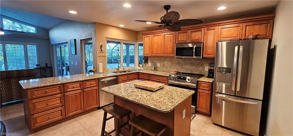 Kitchen featuring stainless steel appliances, a kitchen bar, kitchen peninsula, ceiling fan, and a center island