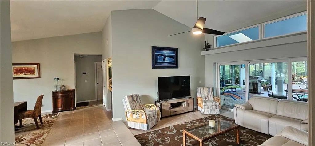 Tiled living room featuring high vaulted ceiling and ceiling fan