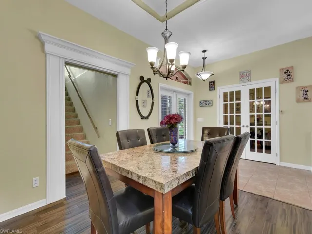 Dining space with dark wood-type flooring, french doors, and a chandelier