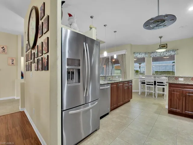 Kitchen featuring appliances with stainless steel finishes, light stone countertops, sink, and decorative light fixtures