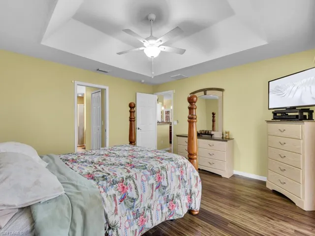 Bedroom featuring a tray ceiling, ceiling fan, and dark wood-type flooring
