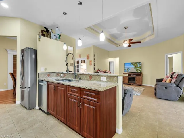Kitchen featuring ceiling fan, appliances with stainless steel finishes, a tray ceiling, and tasteful backsplash