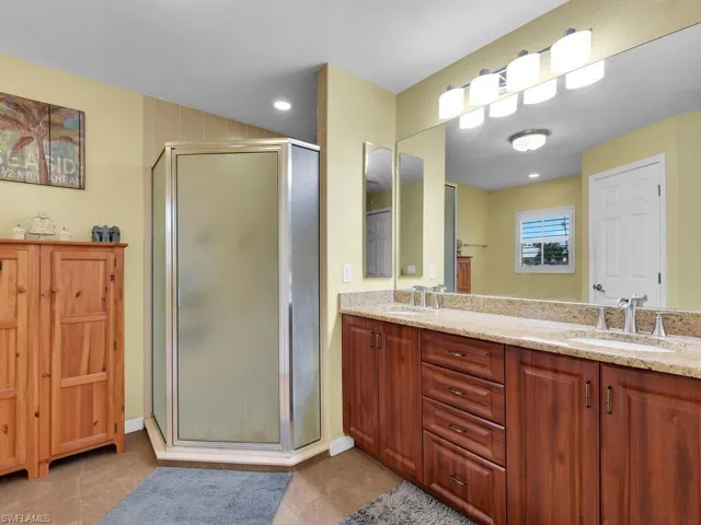 Bathroom with a shower with door, vanity, and tile patterned floors