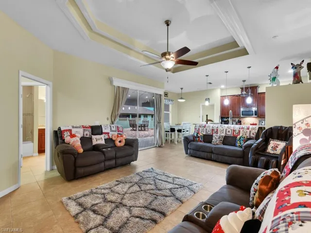 Tiled living room with a tray ceiling and ceiling fan