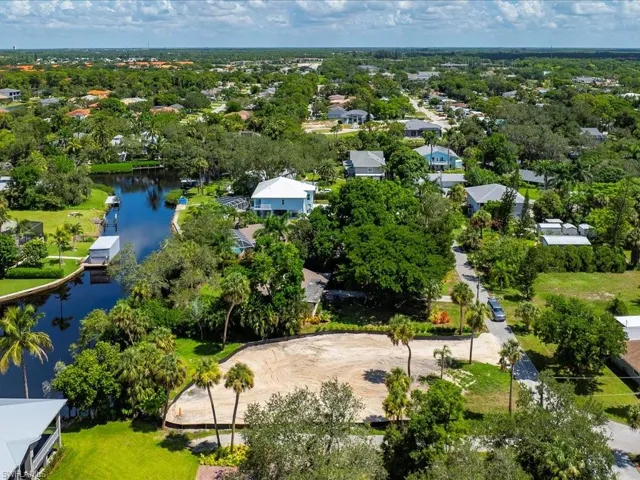 Aerial perspective of suburban area featuring a large body of water and a tree filled landscape