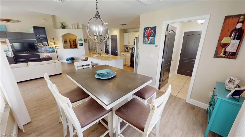 Dining room with light wood-type flooring and a notable chandelier