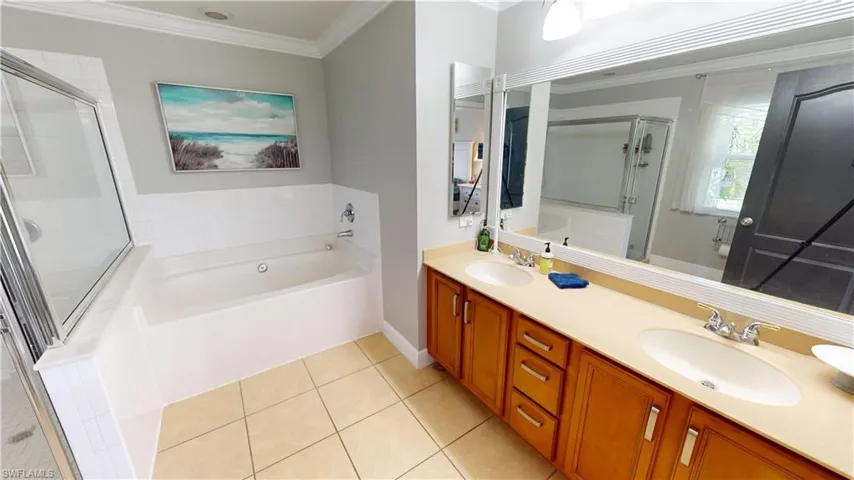 Bathroom featuring tile patterned floors, separate shower and tub, crown molding, and double vanity