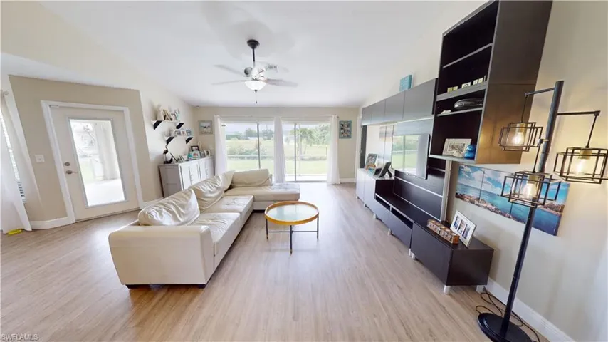 Living room featuring light hardwood / wood-style flooring, ceiling fan, and vaulted ceiling