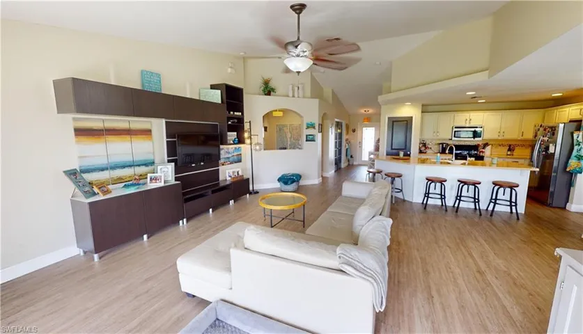 Living room with high vaulted ceiling, sink, light wood-type flooring, and ceiling fan