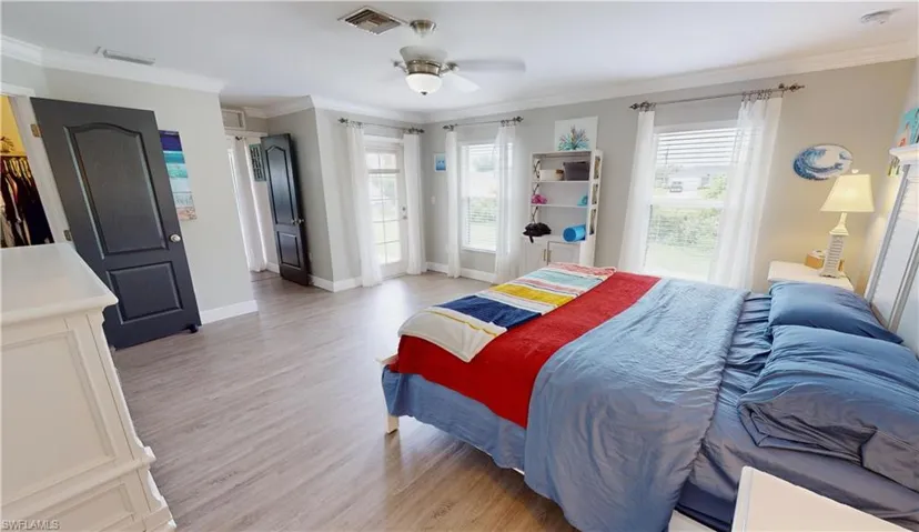 Bedroom featuring light wood-type flooring, ceiling fan, and ornamental molding