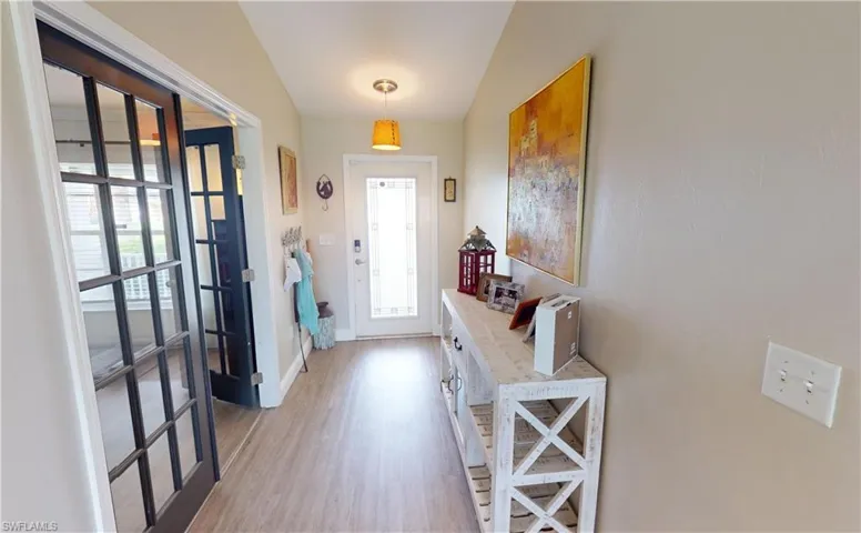 Doorway to outside with hardwood / wood-style floors, lofted ceiling, and a wealth of natural light