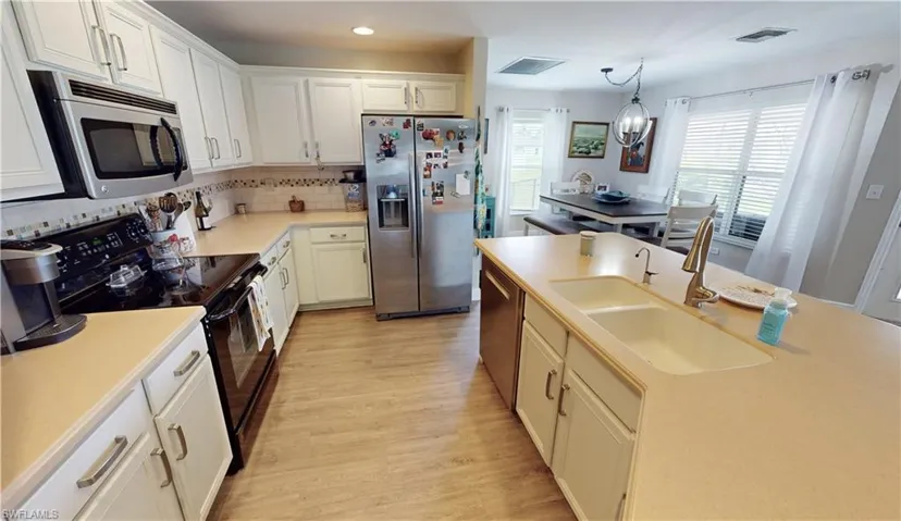Kitchen featuring appliances with stainless steel finishes, light hardwood / wood-style flooring, sink, a kitchen island, and decorative backsplash