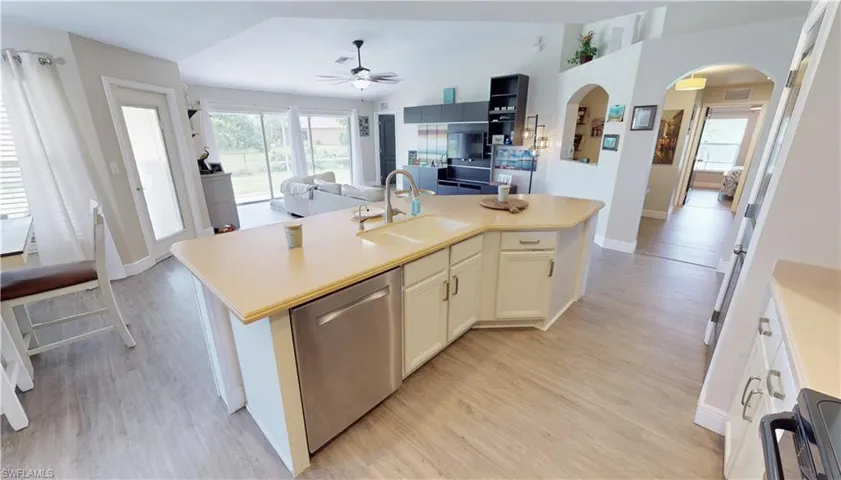Kitchen with dishwasher, light hardwood / wood-style flooring, a kitchen island with sink, and sink