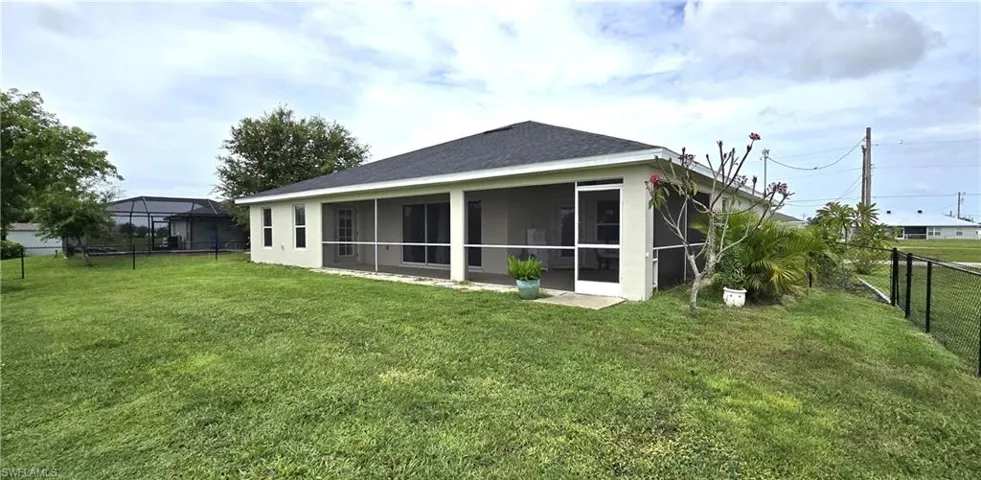 Rear view of property with a sunroom and a lawn