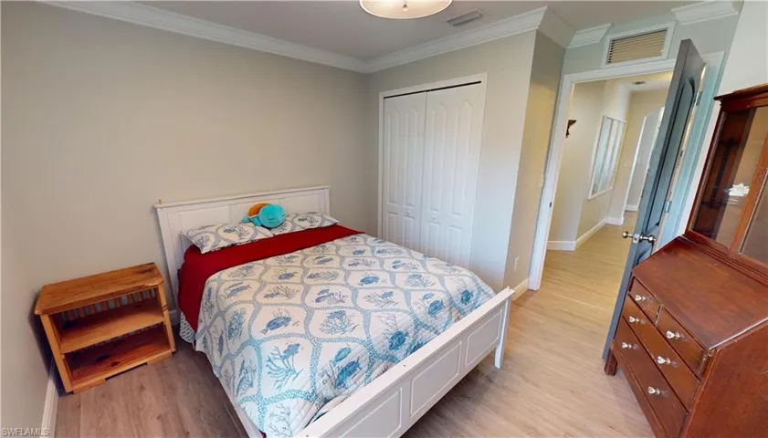 Bedroom with light hardwood / wood-style flooring, a closet, and crown molding