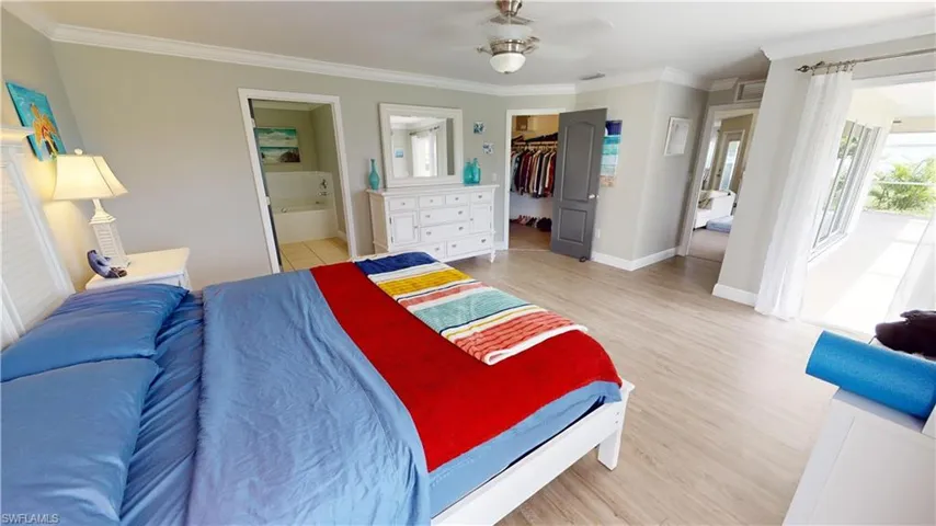 Bedroom featuring a closet, connected bathroom, hardwood / wood-style flooring, a spacious closet, and ornamental molding