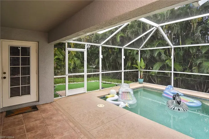 View of pool with a patio area and glass enclosure