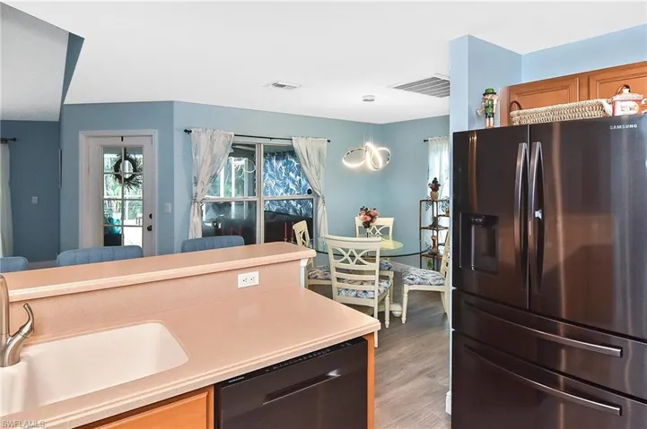 Kitchen with sink, black dishwasher, fridge with ice dispenser, and hardwood / wood-style floors