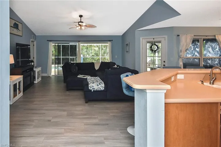 Living room featuring lofted ceiling, sink, ceiling fan, and wood-type flooring