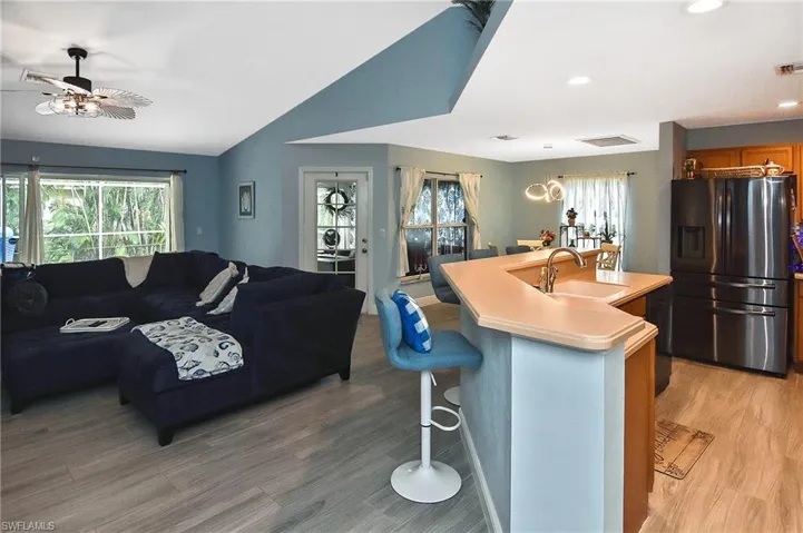 Kitchen featuring a breakfast bar, tile flooring, an island with sink, stainless steel fridge, and sink