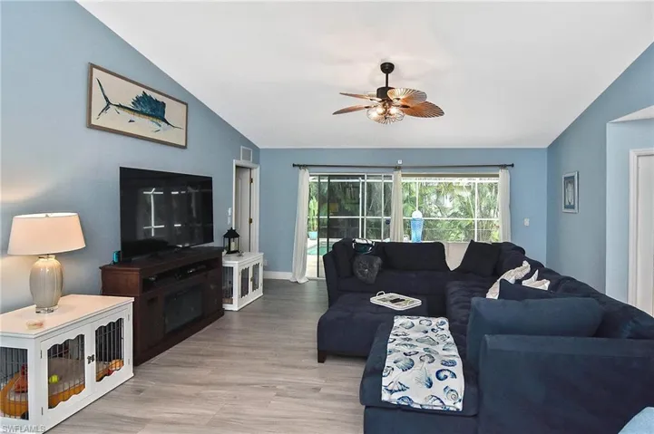 Living room featuring light tile / wood-style flooring, lofted ceiling, and ceiling fan