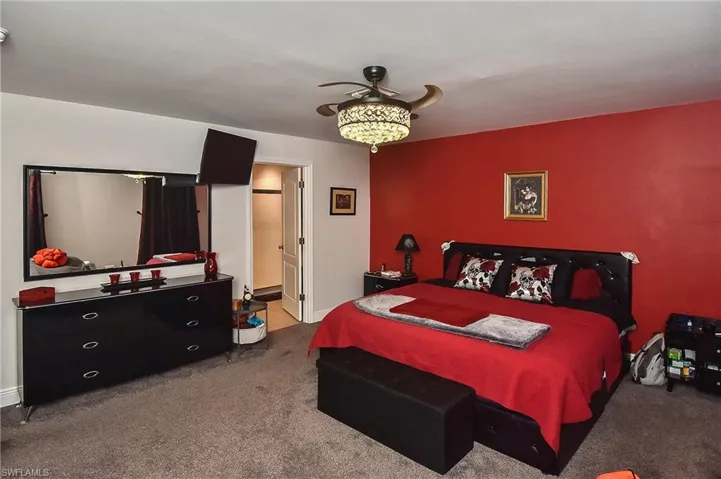 Carpeted bedroom with ensuite bath and ceiling fan