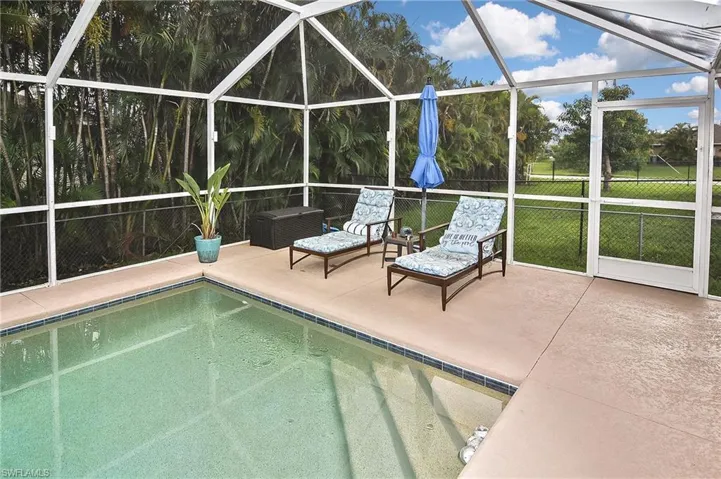 View of pool with central AC unit, glass enclosure, and a patio area