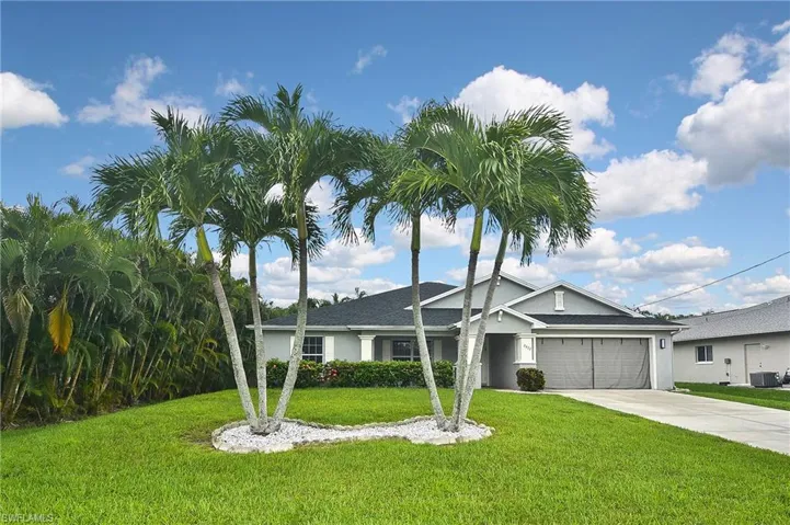 View of front of home featuring a garage, central air condition unit, and a front yard