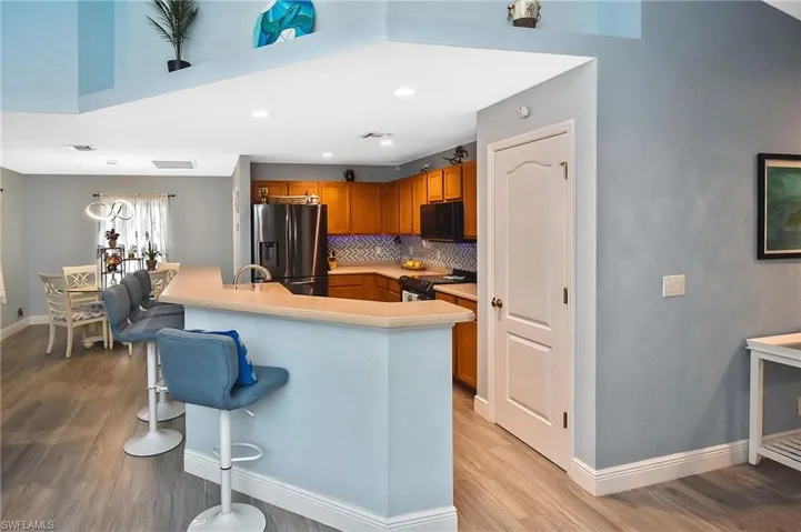 Kitchen with light hardwood / wood-style flooring, black appliances, and decorative backsplash