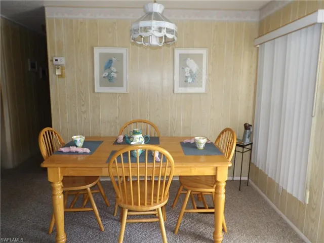 Dining room featuring carpet flooring, wood walls, and a chandelier