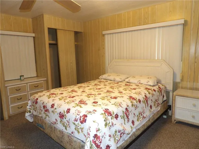 Bedroom featuring ceiling fan, dark colored carpet, and a closet