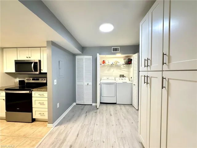 Kitchen with white cabinets, stainless steel appliances, light hardwood / wood-style floors, and independent washer and dryer
