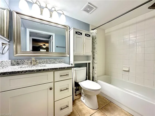Full bathroom with tile patterned flooring, vanity, toilet, and shower / bath combination with curtain