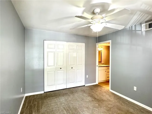 Unfurnished bedroom with ensuite bath, a closet, ceiling fan, and carpet