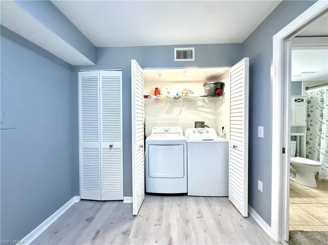 Clothes washing area featuring light hardwood / wood-style flooring and washer and clothes dryer