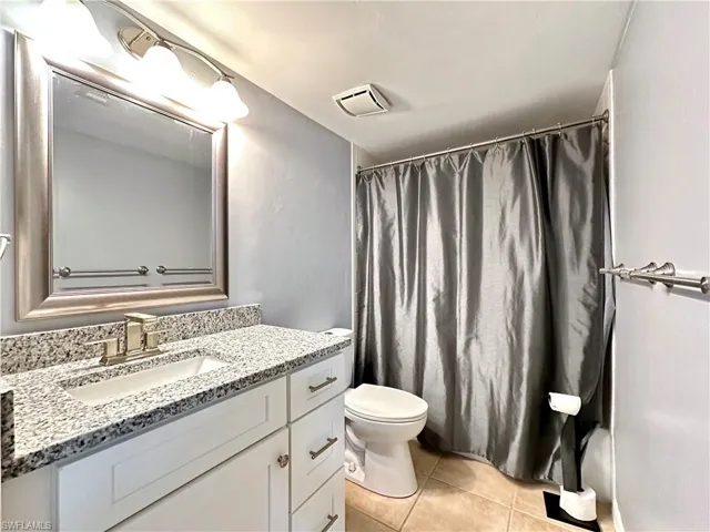 Bathroom with a shower with shower curtain, tile patterned flooring, toilet, and vanity