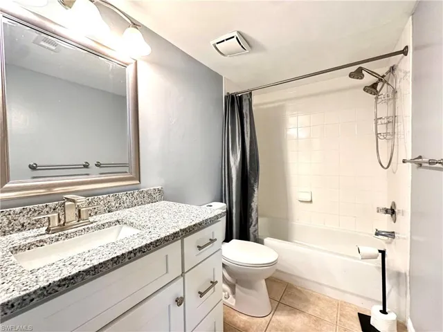 Full bathroom with vanity, toilet, tile patterned flooring, and shower / bathtub combination with curtain