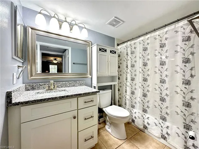 Full bathroom featuring tile patterned flooring, vanity, toilet, and shower / bath combination with curtain